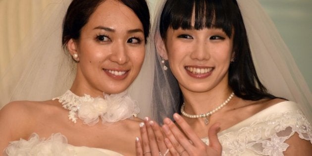 Japanese actress Akane Sugimori (R) and her partner Ayaka Ichinose, both dressed in white, display their wedding rings at a press conference after their marriage ceremony in Tokyo on April 19, 2015. The lesbian couple held a symbolic wedding ceremony in Tokyo, as calls grow for Japan to legalise same-sex marriage. While their marriage will not be recognised under law, actresses Ichinose, 34, and Sugimori, 28 tied the knot in front of some 80 relatives and friends. AFP PHOTO / Yoshikazu TSUNO (Photo credit should read YOSHIKAZU TSUNO/AFP/Getty Images)