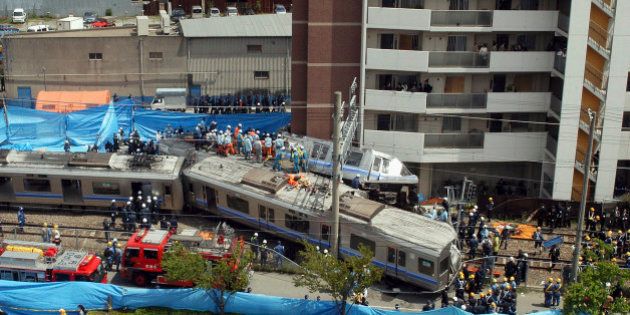 AMAGASAKI, JAPAN - APRIL 25: Rescue workers attempt to free trapped passengers from a crushed commuter train after it derailed and plowed into an apartment building on April 25, 2005 in Amagasaki, Hyogo prefecture, Japan. 49 people have so far been confirmed as dead. (Photo by Getty Images)