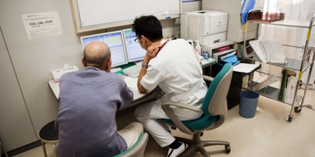 Kojiro Tokutake, a gastroenterologist at Nagano Prefectural Suzaka Hospital, right, discusses diagnostic test results with a patient at the hospital in Suzaka, Nagano Prefecture, Japan, on Friday, Nov. 8, 2013. Tokutake wanted to be a doctor since he was a teenager. His grandmother bought him his first stethoscope when he was in medical school. A decade later, he helped her die. Photographer: Ko Sasaki/Bloomberg via Getty Images