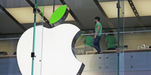 Employees wear green shirts near Apple's familiar logo displayed with a green leaf at the Apple Store timed to coincide with Tuesday's annual celebration of Earth Day in Sydney, Tuesday, April 22, 2014. Apple is offering free recycling of all its used products and vowing to power all of its stores, offices and data centers with renewable energy to reduce the pollution caused by its devices and online services. (AP Photo/Rick Rycroft)