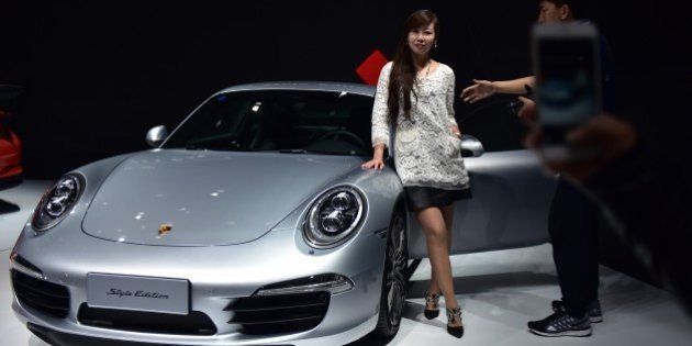 A woman poses next to a Porsche 911 Carrera Style Edition at the 16th Shanghai International Automobile Industry Exhibition in Shanghai on April 20, 2015. Global car makers showed off hundreds of vehicles in China's commercial hub Shanghai on April 20, as the world's biggest auto market continues to attract despite a sharp deceleration in sales growth. AFP PHOTO / JOHANNES EISELE (Photo credit should read JOHANNES EISELE/AFP/Getty Images)