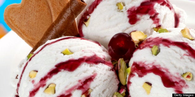 Vanilla ice cream balls with cherry syrup and pieces of pistachio