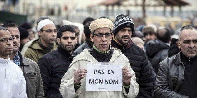 A Muslim man holds a placard, reading 'Not in my name', during a gathering on January 9, 2015 near the mosque of Saint-Etienne, eastern France, after the country's bloodiest attack in half a century on the offices of the weekly satirical Charlie Hebdo killing 12 people on January 7. AFP PHOTO / JEAN-PHILIPPE KSIAZEK (Photo credit should read JEAN-PHILIPPE KSIAZEK/AFP/Getty Images)