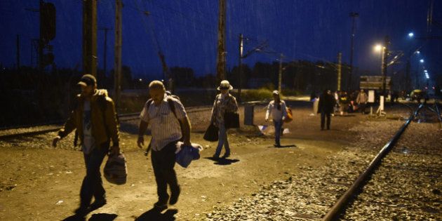 Refugees and migrants walk under heavy rain to cross into southern Macedonia from Idomeni, Greece, Monday, Sept. 21, 2015. Hundreds of refugees and economic migrants arrive daily in the small village of some 100 inhabitants to cross into Macedonia, from where they continue through Serbia and Hungary to seek asylum in wealthier European countries. (AP Photo/Giannis Papanikos)