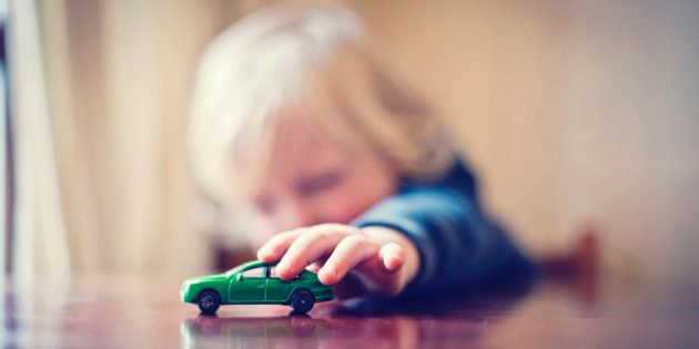 Little boy playing with toy car.