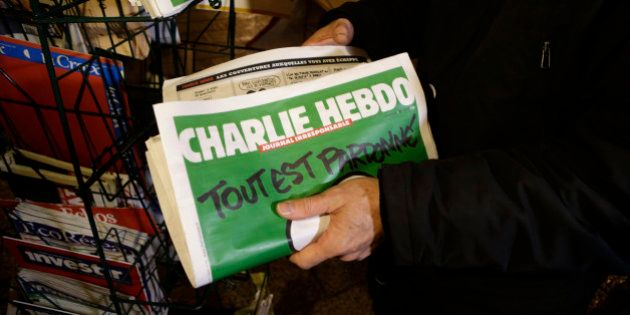 A seller of newspapers installs in shelf, several Charlie Hebdo newspapers at a newsstand in Nice southeastern France, Wednesday, Jan. 14, 2015. On front page reading