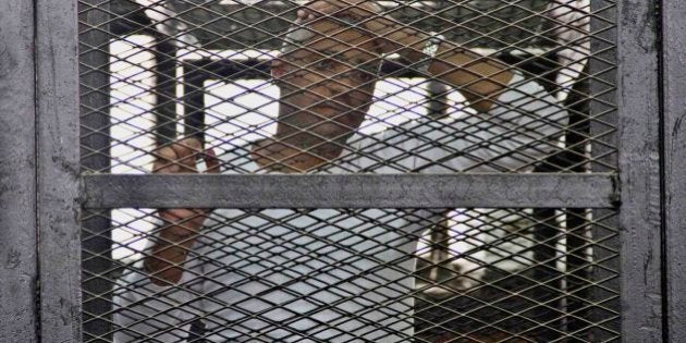 Canadian-Egyptian acting Al-Jazeera bureau chief Mohammed Fahmy appears in a defendant's cage in a courthouse near Tora prison along with other defendants during a trial on terror charges in Cairo, Egypt, Saturday, May 3, 2014. Fahmy made a rare appeal to the judge from outside of the defendants' cage, at the end of which the judge wished him a