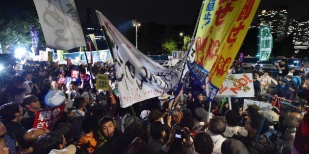 Demonstrators hold placards during a protest against Prime Minister Shinzo Abe's controversial security bills in front of the National Diet in Tokyo on September 16, 2015. Japan is set to enact controversial security bills that opponents say will undermine 70 years of pacifism and could see Japanese troops fighting abroad for the first time since World War II. AFP PHOTO / KAZUHIRO NOGI (Photo credit should read KAZUHIRO NOGI/AFP/Getty Images)