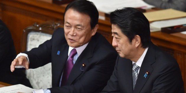 Japanese Finance Minister Taro Aso (L) speaks with Prime Minister Shinzo Abe (R) during a session at the National Diet in Tokyo on January 26, 2015. The National Diet convened a 150-day session with Finance Minister Taro Aso delivering a speech. AFP PHOTO / KAZUHIRO NOGI (Photo credit should read KAZUHIRO NOGI/AFP/Getty Images)