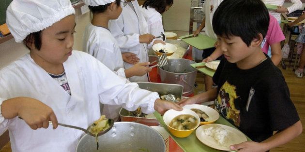 Students in protective kitchen attire serve lunch to their classmates at the Dai Nana Sunamachi Elementary School in Tokyo. (AP Photo/Toru Takahashi)