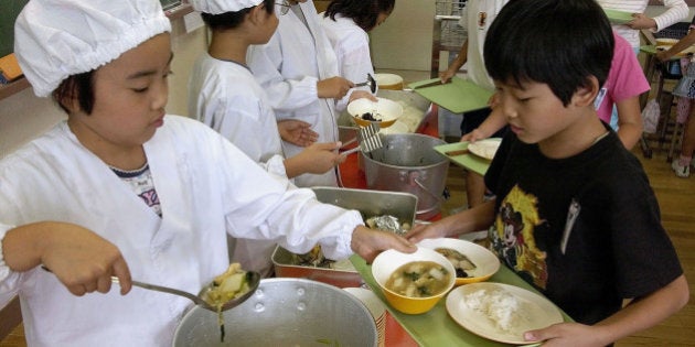 Students in protective kitchen attire serve lunch to their classmates at the Dai Nana Sunamachi Elementary School in Tokyo. (AP Photo/Toru Takahashi)