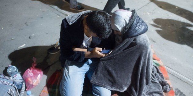 Migrants use a smartphone as they rest near the village of Nickelsdorf at the Hungarian-Austrian border in early hours on September 5, 2015 from where they head to Salzburg on the German-Austrian border. The refugees began arriving at the Austrian border in the night after Hungary, which has become one of the newest flashpoints in Europe's migrant crisis, began bussing people who had been stuck in the capital Budapest.AFP PHOTO / JOE KLAMAR (Photo credit should read JOE KLAMAR/AFP/Getty Images)