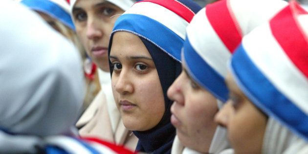 Young women wear headbands in the colors of the French flag as hundreds of Muslims take to the streets in Paris Saturday, Jan. 17, 2004, to protest the government's plan to ban religious attire in public schools. The proposed law would ban Muslim head scarves, Jewish skullcaps and large Christian crosses from public schools to keep them secular and avoid religious strife. (AP Photo/Laurent Rebours)