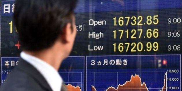 A pedestrian looks at a stock market share prices board in Tokyo on November 4, 2014. Tokyo's Nikkei 225 index ended at a fresh seven-year high on November 4 in the wake of last week's surprise decision by the Bank of Japan to expand its asset-buying programme. AFP PHOTO / KAZUHIRO NOGI (Photo credit should read KAZUHIRO NOGI/AFP/Getty Images)