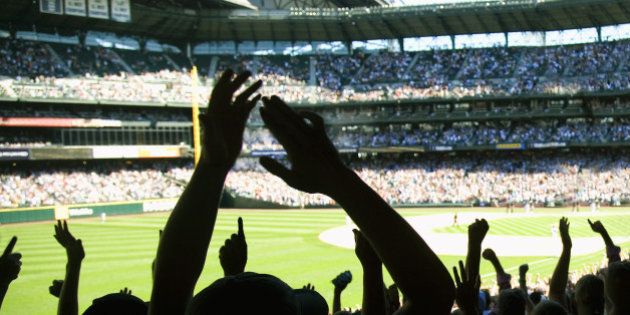 Baseball fans cheering in stadium.