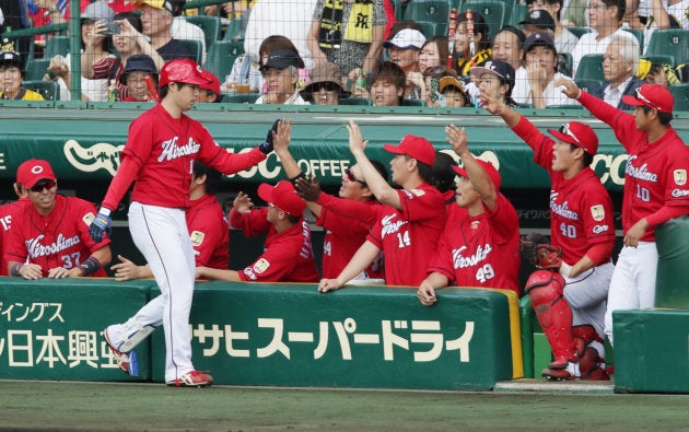 4回、スクイズを決め、ナインに迎えられる広島の野村（左手前）＝18日、甲子園