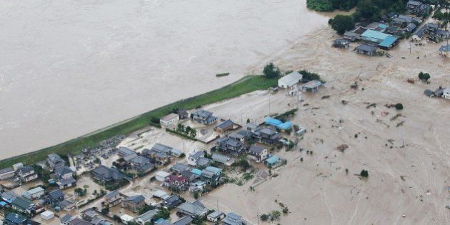 Floodwaters from the burst Kinugawa river (L) flow into a residential area (R) in Joso, Ibaraki Prefecture, on September 10, 2015. The Japanese city 50 km north east of Tokyo was flooded when Kinugawa river burst its banks, destroying homes and cars as desperate residents waited for help, and as thousands of people were ordered to evacuate. AFP PHOTO/Jiji Press JAPAN OUT (Photo credit should read JIJI PRESS/AFP/Getty Images)