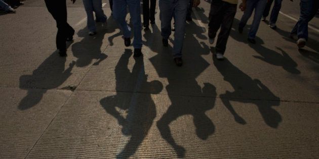 The shadow of electricians is cast on the road as they protest the government's shut down of a state-run power company in Mexico City