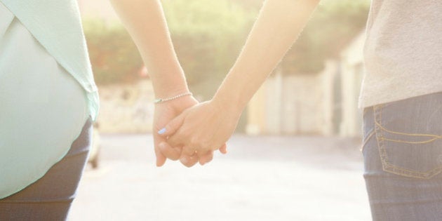 Lesbian Holding Hands and Walking in a street. Rear view.