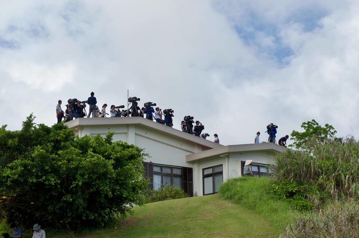 現場への立ち入りを制限され、規制線の外の民家の屋根から取材する報道関係者ら＝10月12日、沖縄県東村高江