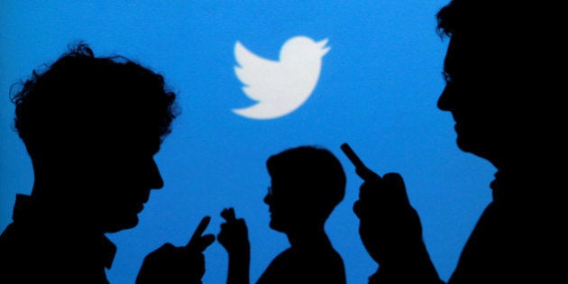 FILE PHOTO -- People holding mobile phones are silhouetted against a backdrop projected with the Twitter logo in this illustration picture taken in Warsaw September 27, 2013. REUTERS/Kacper Pempel/Illustration/File Photo