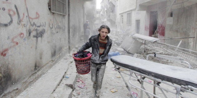 A boy carries his belongings at a site hit by what activists said was a barrel bomb dropped by forces loyal to Syria's President Bashar al-Assad in Aleppo's al-Fardous district April 2, 2015. REUTERS/Rami Zayat TPX IMAGES OF THE DAY