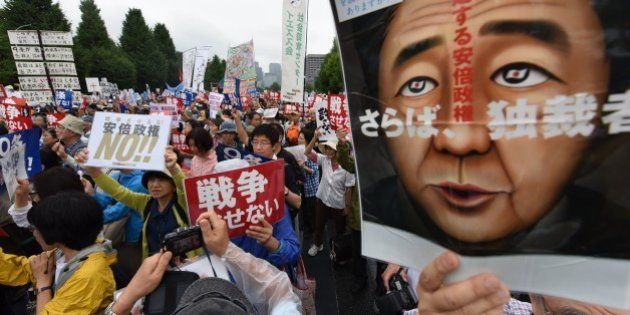 People shout slogans as they hold banners during an anti-government rally in front of the National Diet in Tokyo on August 30, 2015 to protest against Japan's Prime Minister Shinzo Abe's controversial security bills which would expand the remit of the country's armed forces. Tens of thousands of people took part in the rallies held around the Diet. AFP PHOTO / Toru YAMANAKA (Photo credit should read TORU YAMANAKA/AFP/Getty Images)