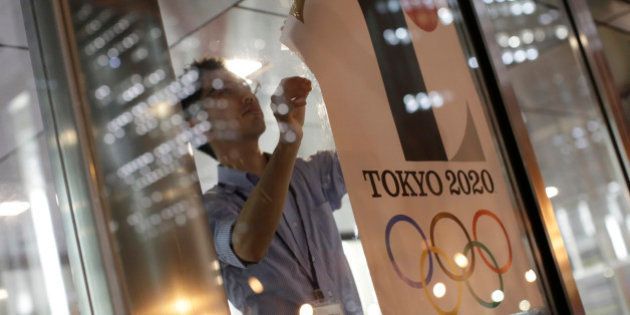The poster with a logo of Tokyo Olympic Games 2020 is removed from the wall by a worker during an event staged for photographers at the Tokyo Metropolitan Government building in Tokyo Tuesday, Sept. 1, 2015. Tokyo Olympic organizers on Tuesday decided to scrap the logo for the 2020 Games following another allegation its Japanese designer might have used copied materials.(AP Photo/Eugene Hoshiko)
