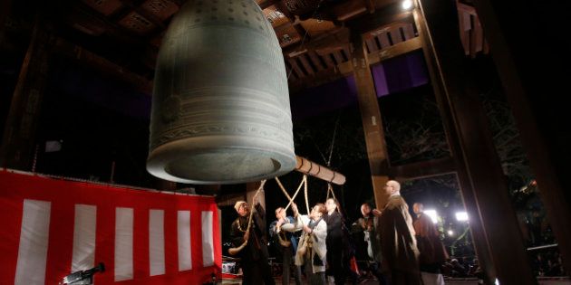 People strike a giant bell to celebrate the New Year at Zojoji Buddhist temple, in Tokyo, early Wednesday, Jan. 1, 2014. (AP Photo/Shizuo Kambayashi)