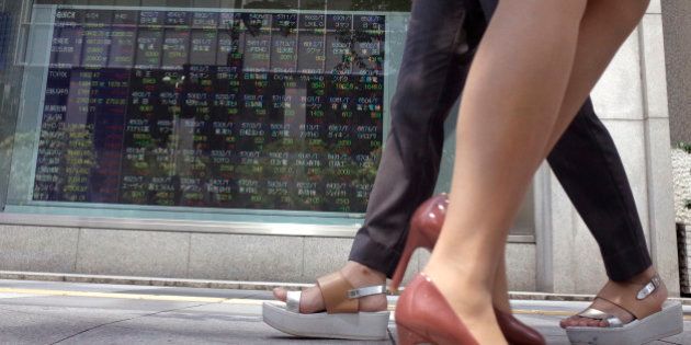 Women walk past an electronic stock indicator of a securities firm showing Tokyo's Nikkei 225 in Tokyo, Wednesday, June 24, 2015. (AP Photo/Shuji Kajiyama)