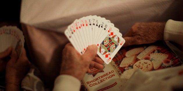 A British retiree living in Spain holds poker cards while playing bingo with other compatriots after winning a cookies package as they gather for a coffee morning organised by a charity at a bar in Fuengirola, near Malaga, southern Spain, November 17, 2016. Picture taken November 17, 2016. To match Insight BRITAIN-EU/SPAIN REUTERS/Jon Nazca