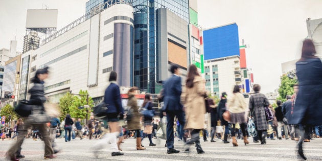 People walking over famous zebra crossing at Shibuya Crossing in Downtown Tokyo. Long exposure. Motion Blurred People. Tokyo, Japan.