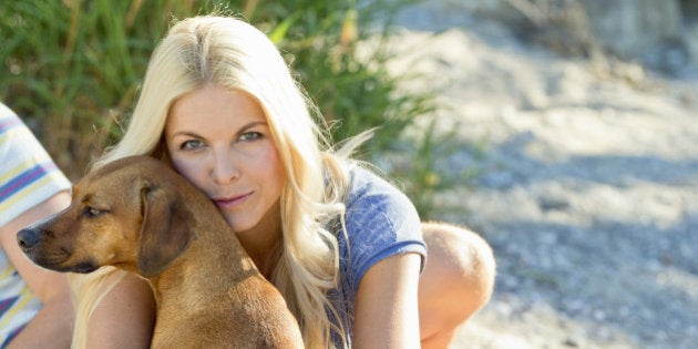 Woman with boyfriend and dog sitting on a blanket outdoor.