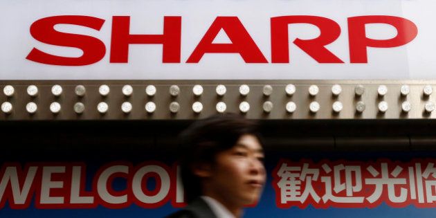A logo of Sharp Corp is seen above a Chinese tourist standing outside an electronics retail store in Tokyo, Japan, March 30, 2016. REUTERS/Yuya Shino