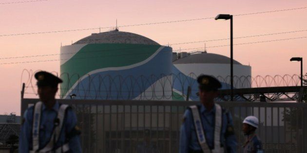 Nuclear reactor buildings of the Kyushu Electric Power Sendai nuclear power plant are seen behind police officers standing guard in the twilight in Satsumasendai in Kagoshima prefecture, on Japan's southern island of Kyushu on August 11, 2015. Japan on August 11 switched on a nuclear reactor, officials said, ending a two-year shutdown in the energy-hungry country that was sparked by public fears following the 2011 Fukushima crisis, the worst atomic disaster in a generation. AFP PHOTO / JIJI PRESS JAPAN OUT (Photo credit should read JIJI PRESS/AFP/Getty Images)