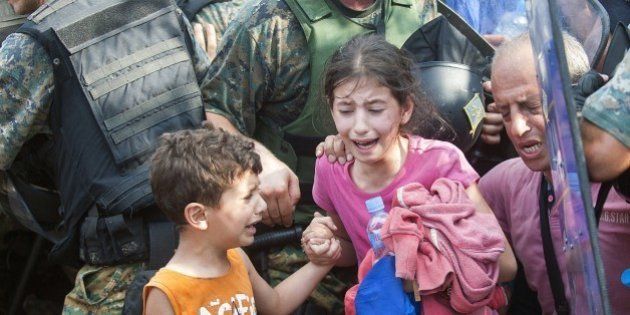 A young girl and boy cry as police block a group of migrants trying to cross the Macedonian-Greek border near the town of Gevgelija on August 21, 2015. Macedonia said on August 20 that it had declared a 'state of emergency' on its southern border with Greece and would draft in the army to help control the influx of migrants crossing the frontier. AFP PHOTO / ROBERT ATANASOVSKI (Photo credit should read ROBERT ATANASOVSKI/AFP/Getty Images)