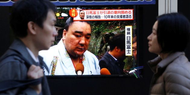 People walk past a street monitor showing Sumo grand champion Harumafuji, in Tokyo, Japan, November 29, 2017. REUTERS/Toru Hanai