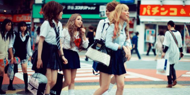 Japanese school girls with funky and crazy hair styles and mini skirts crossing the street in Shibuya, Tokyo.