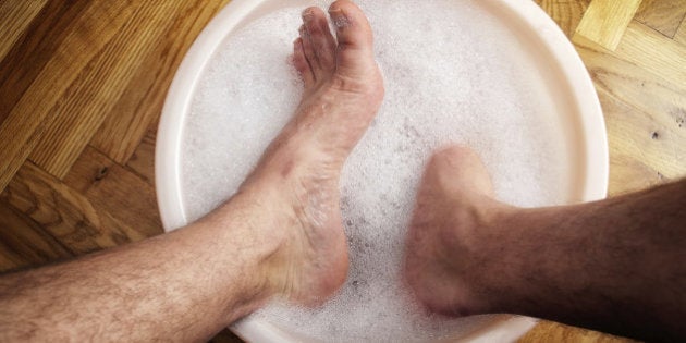 Man soaking his feet in a washbowl.