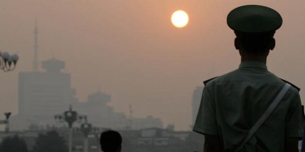 BEIJING, CHINA: A paramilitary policeman faces the sunrise while patrolling Tiananmen Square on a hazy morning in Beijing, early 09 September 2005. As Chinese President Hu Jintao started his first visit to North America since becoming the ruling Communist Party's top leader, he is likely to be pressed over China's huge pollution output. China's refusal to cut emissions would set a poor example for developing nations when Kyoto Protocol signatories meet in Montreal in December, Canadian officials said. AFP PHOTO/Frederic J. BROWN (Photo credit should read FREDERIC J. BROWN/AFP/Getty Images)