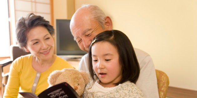 Girl with grandparents looking at brochure, smiling