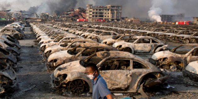 In this photo taken Thursday, Aug. 13, 2015, a man walks past the charred remains of new cars at a parking lot near the site of an explosion at a warehouse in northeastern China's Tianjin municipality. Rescuers have pulled a survivor from an industrial zone about 32 hours after it was devastated by huge blasts in Chinaâs Tianjin port. Meanwhile, authorities are moving gingerly forward in dealing with a fire still smoldering amid potentially dangerous chemicals. (AP Photo/Ng Han Guan)