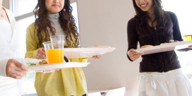 Three young women in cafeteria, smiling