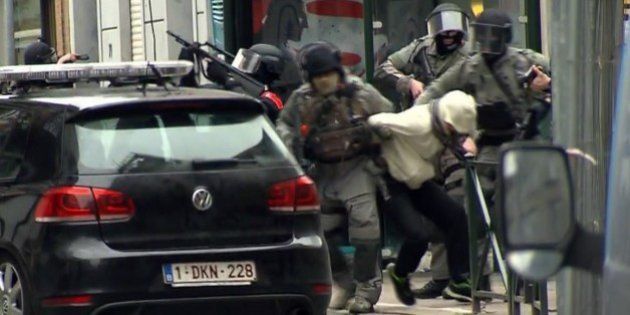 In this framegrab taken from VTM, armed police officers escort a suspect to a police vehicle during a raid in the Molenbeek neighborhood of Brussels, Belgium, Friday March 18, 2016. After an intense four-month manhunt across Europe and beyond, police on Friday captured Salah Abdeslam, the top fugitive in the Paris attacks in the same Brussels neighborhood where he grew up. (VTM via AP) BELGIUM OUT