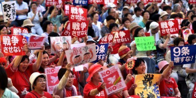 Civic group members hold placards and chant anti-government slogans in Tokyo on July 14, 2015 to protest against Prime Minister Shinzo Abe's controversial security bills. Abe, a robust nationalist, has pushed for what he calls a normalisation of Japan's military posture and wants to loosen restrictions that have bound the so-called Self-Defense Forces to a narrowly defensive role for decades. AFP PHOTO / Yoshikazu TSUNO (Photo credit should read YOSHIKAZU TSUNO/AFP/Getty Images)