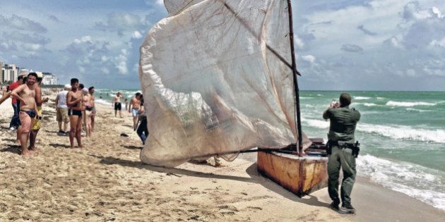 A U.S. Border Patrol agent photographs a boat with a makeshift sail that a group of Cuban migrants used to make landfall on Miami Beach on Tuesday, Sept. 15, 2015. (C.M. Guerrero/El Nuevo Herald/TNS via Getty Images)