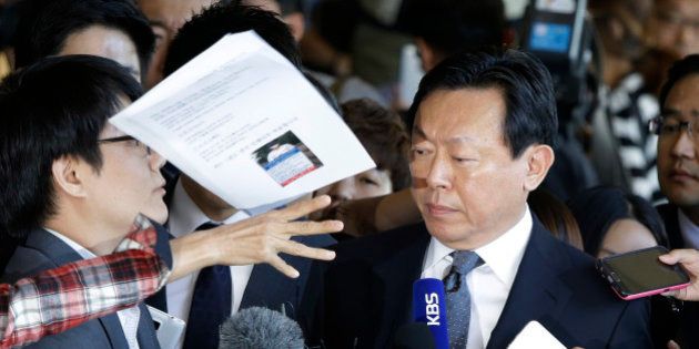 In this Tuesday, Sept. 20, 2016 photo, a bunch of papers is hurled by an unidentified man toward Lotte Group's Chairman Shin Dong-bin, center, as he arrives at the Seoul Central District Prosecutors' Office for the questioning over suspected embezzlement, in Seoul, South Korea. South Korean prosecutors questioned Shin on Tuesday in a corruption probe at the country's fifth-largest business group. (AP Photo/Ahn Young-joon, File)