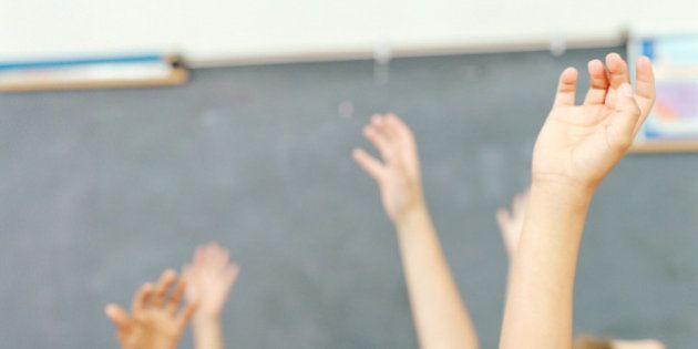 Children's arms raised in classroom
