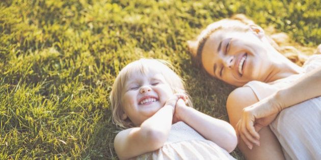 Smiling mother and baby laying on meadow