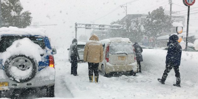大雪で動けなくなった乗用車とドライバーら＝６日午前、福井市内の国道８号※車のナンバーにモザイクをかけてあります